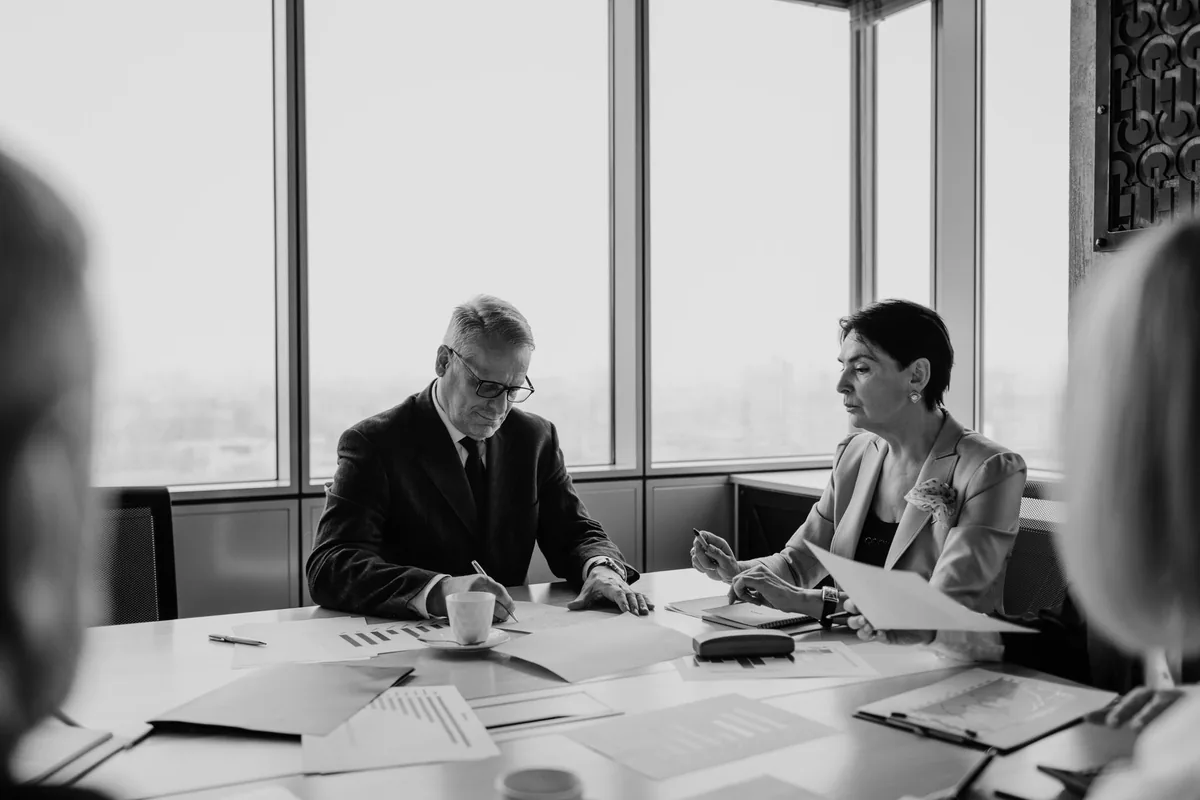 Deux associés signant un accord autour d'une table de réunion avec des documents juridiques